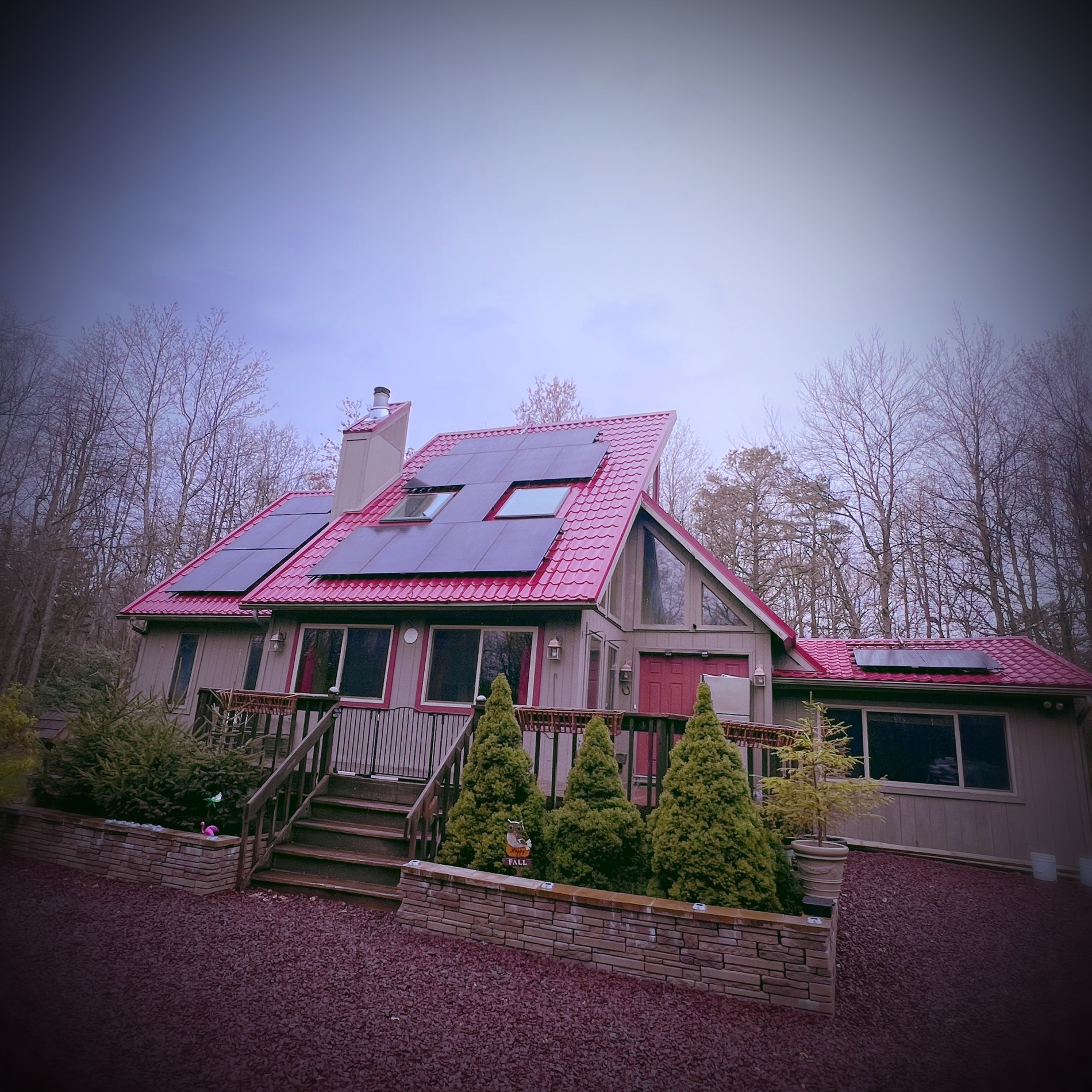 A chalet home with black solar panels on a red metal roof