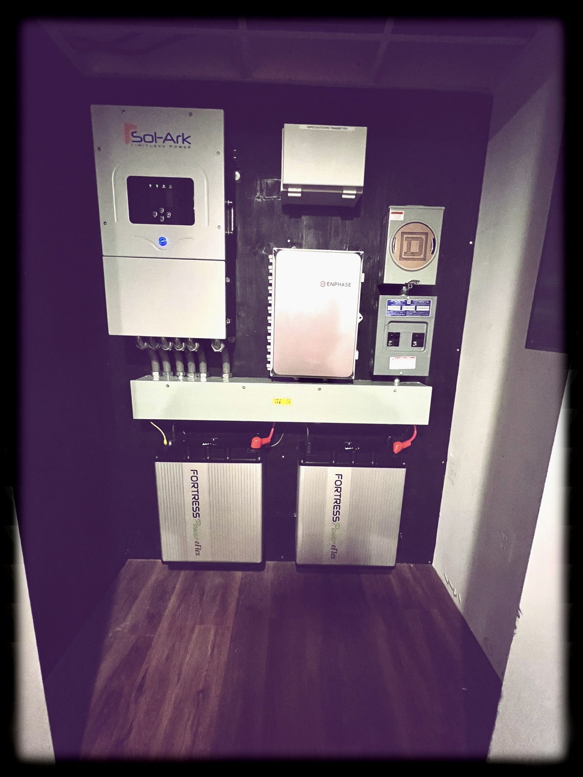 Sol-Ark hybrid inverter, system controller, rapid shutdown transmitter and two wall-mounted Fortress Power batteries in a finished utility room in a Tri-State home