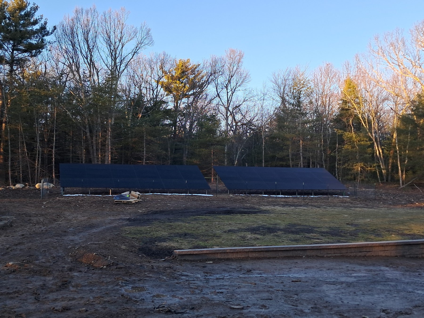 Ground-mounted solar array in an open rural yard with a treeline behind it in the Tri-State area